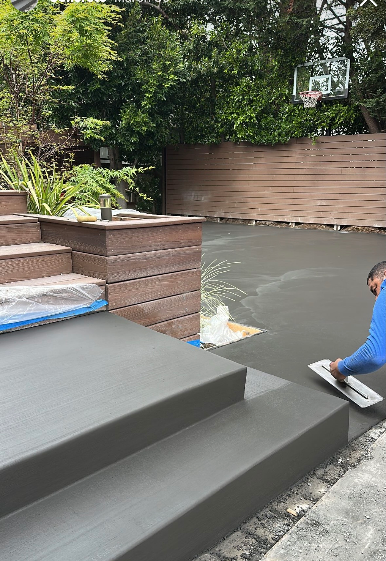 CHR crew finishing a charcoal concrete patio and steps beside a wood deck and fence